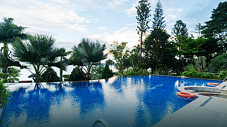 A swimming pool surrounded by trees at Coorg Jungle Camp Backwater Resort, Kushalnagar.