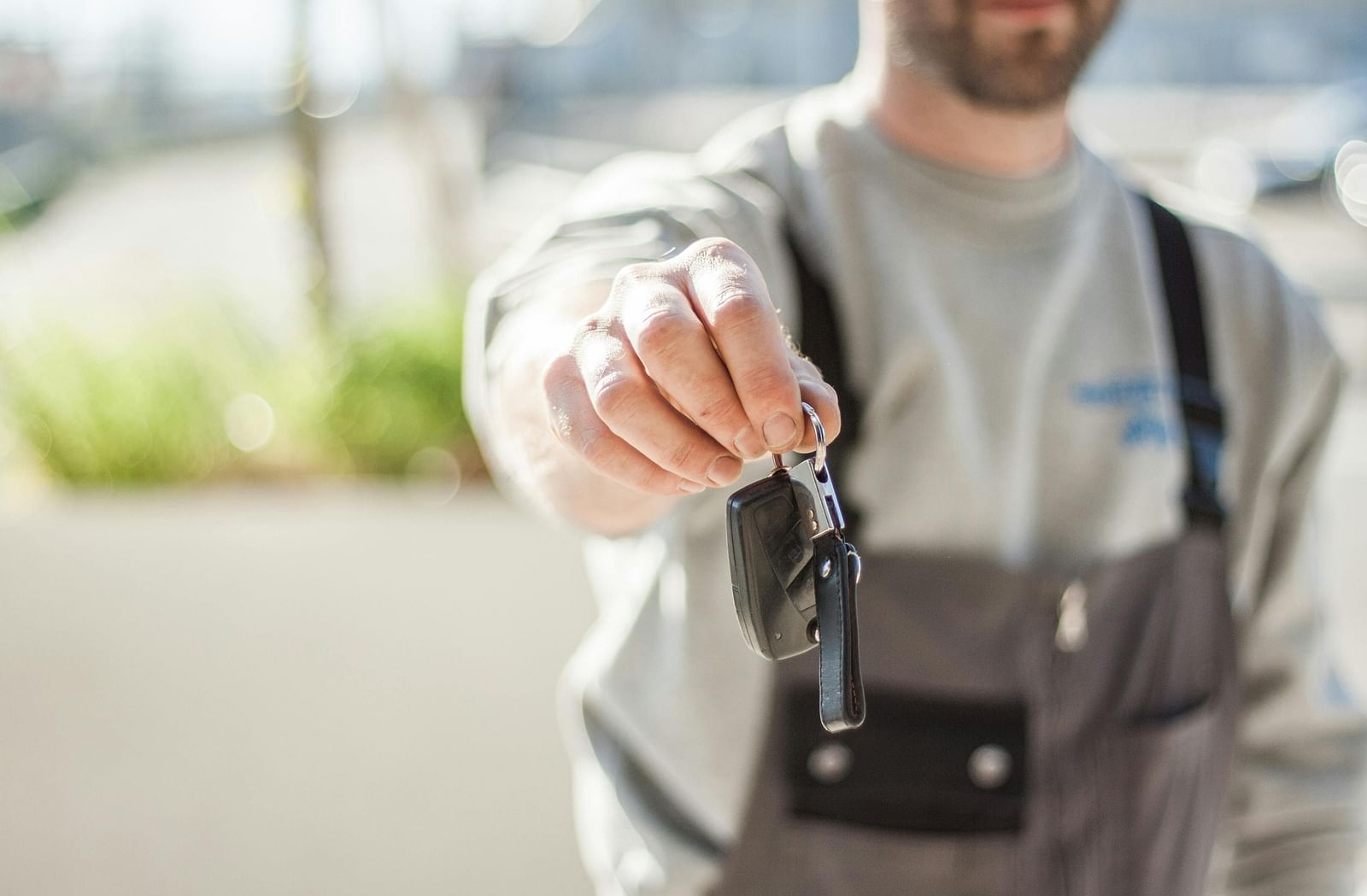 a close up shot of a person handing over car keys with the background blurred.