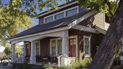 A view of Main Street Suites entrance of Tallman Hotel with a large tree trunk nearby.