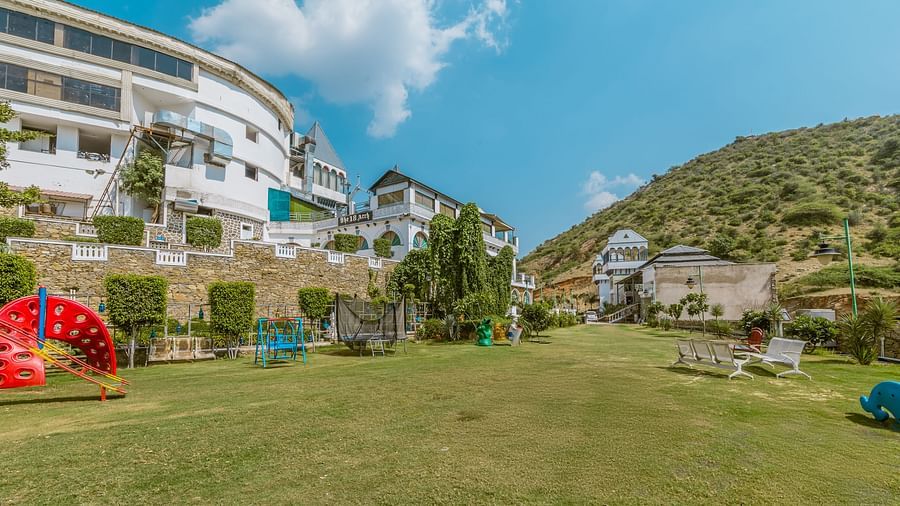 A large lawn area in front of a hotel and a small hill on the side view