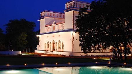 A facade image of Bijay Niwas Palace at night seen from the side of a pool