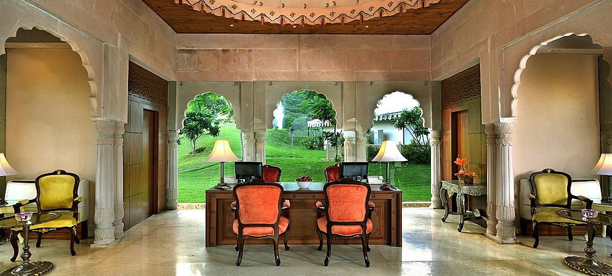 Image of the lobby at Rajasthali Resort & Spa Jaipur with chairs, tables, and a chandelier hanging from the ceiling.