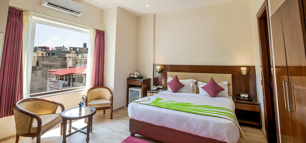 Full view shot of the Deluxe room featuring a double bed along with beautiful city views from the window at Regenta Inn DLS.