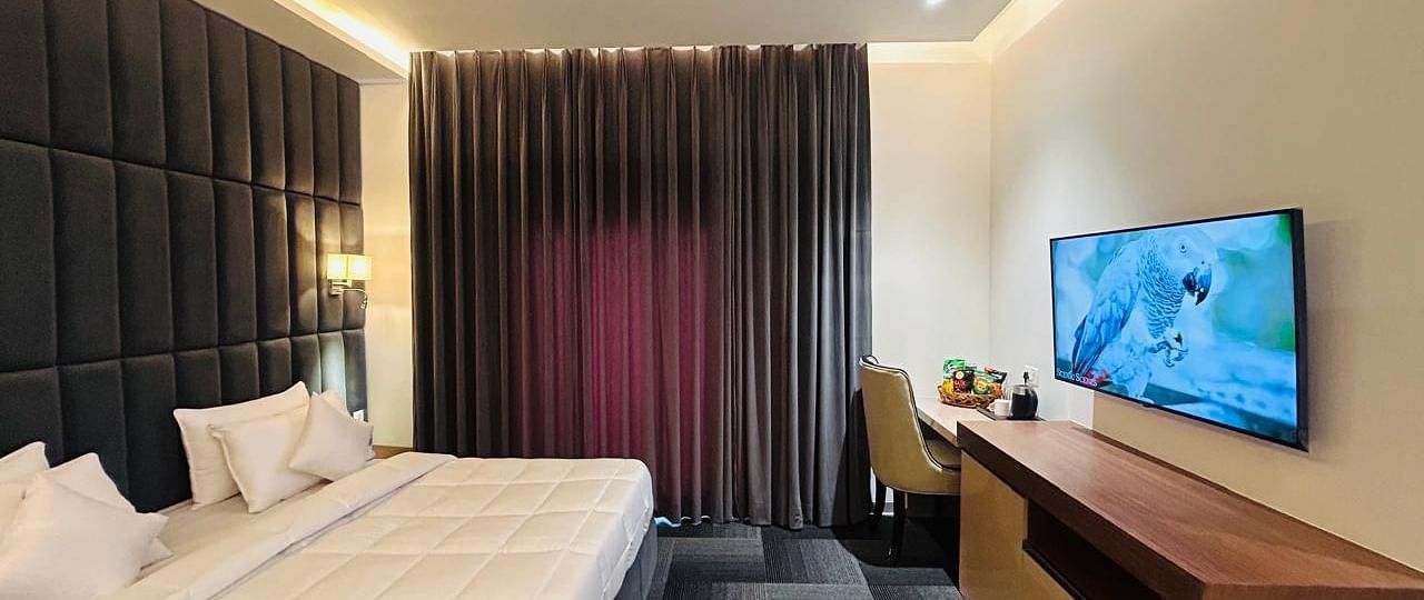 full view image of the executive room with a plush double bed and a wall mounted television at Eminence The Corbett