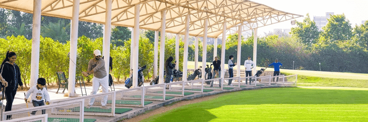 Driving Range at Karma Lakelands with a covered practice area and lush green fairway,  it is accessible with a Delhi Golf Course Membership.