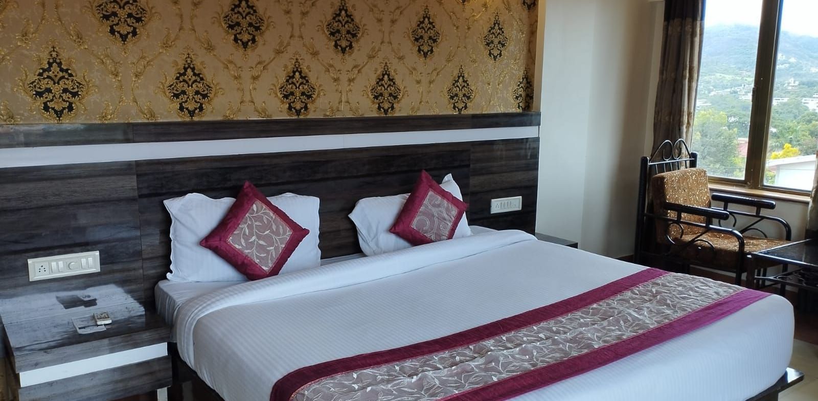 The Super Deluxe Room of Mountview Resort features a king size bed, bedside tables, and a seating area beside the glass windows that offer views of the natural surroundings.