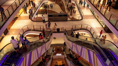 Multi-level shopping mall interior with curved balconies and people walking below.