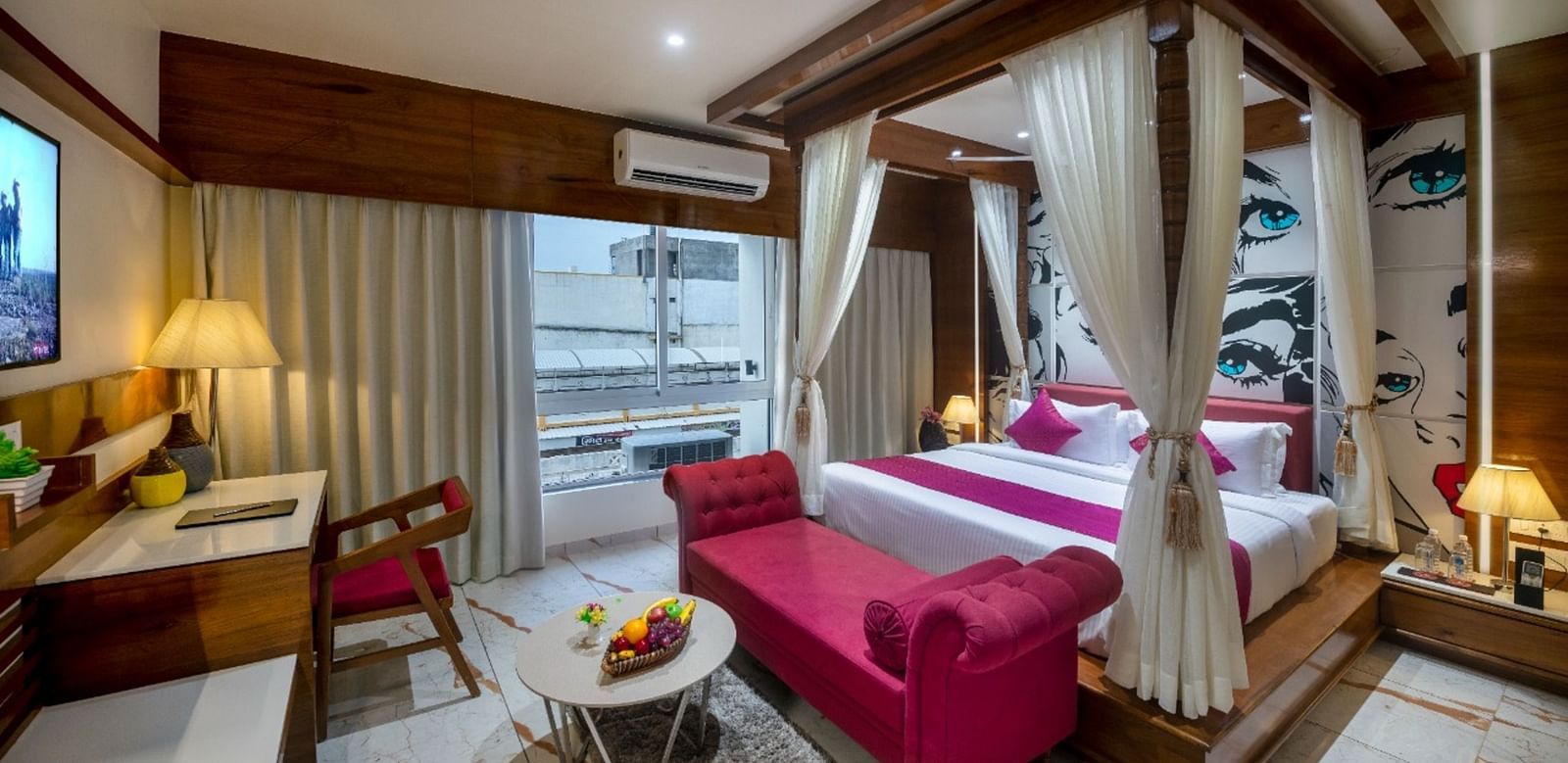 A room with a spacious bed, a small table with chairs, and a window with curtains at Angel Lords Eco Inn Amreli.