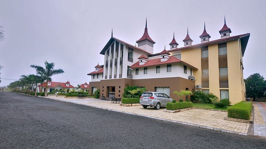 Daytime view of the facade of our hotel with manicured gardens and a vehicle parked right at the front of it - Vishal Lords Inn Gir Forest
