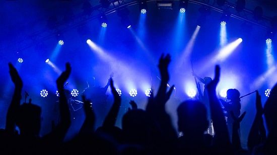 A close shot of people in a room of saturated lights puttings hands up and dancing