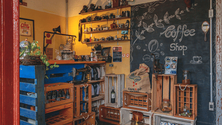 Cozy coffee shop interior featuring vintage cameras, wooden crates, chalkboard wall art, and rustic décor.