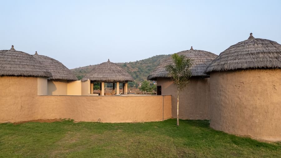Earth Villa exterior, with multiple hut structures connected, and surrounded by a grass lawn.