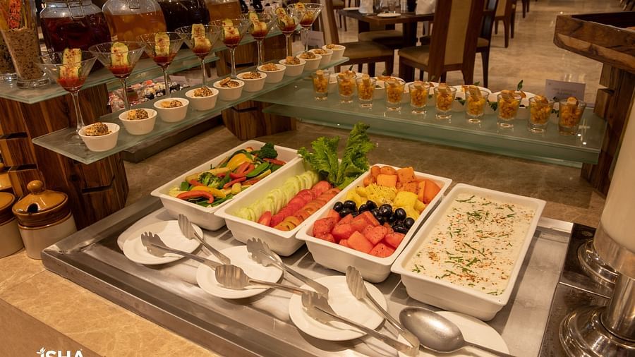 A beverage or salad bar area within the dining space of The Gaurs Sarovar Premiere, with various ingredients and serving utensils.
