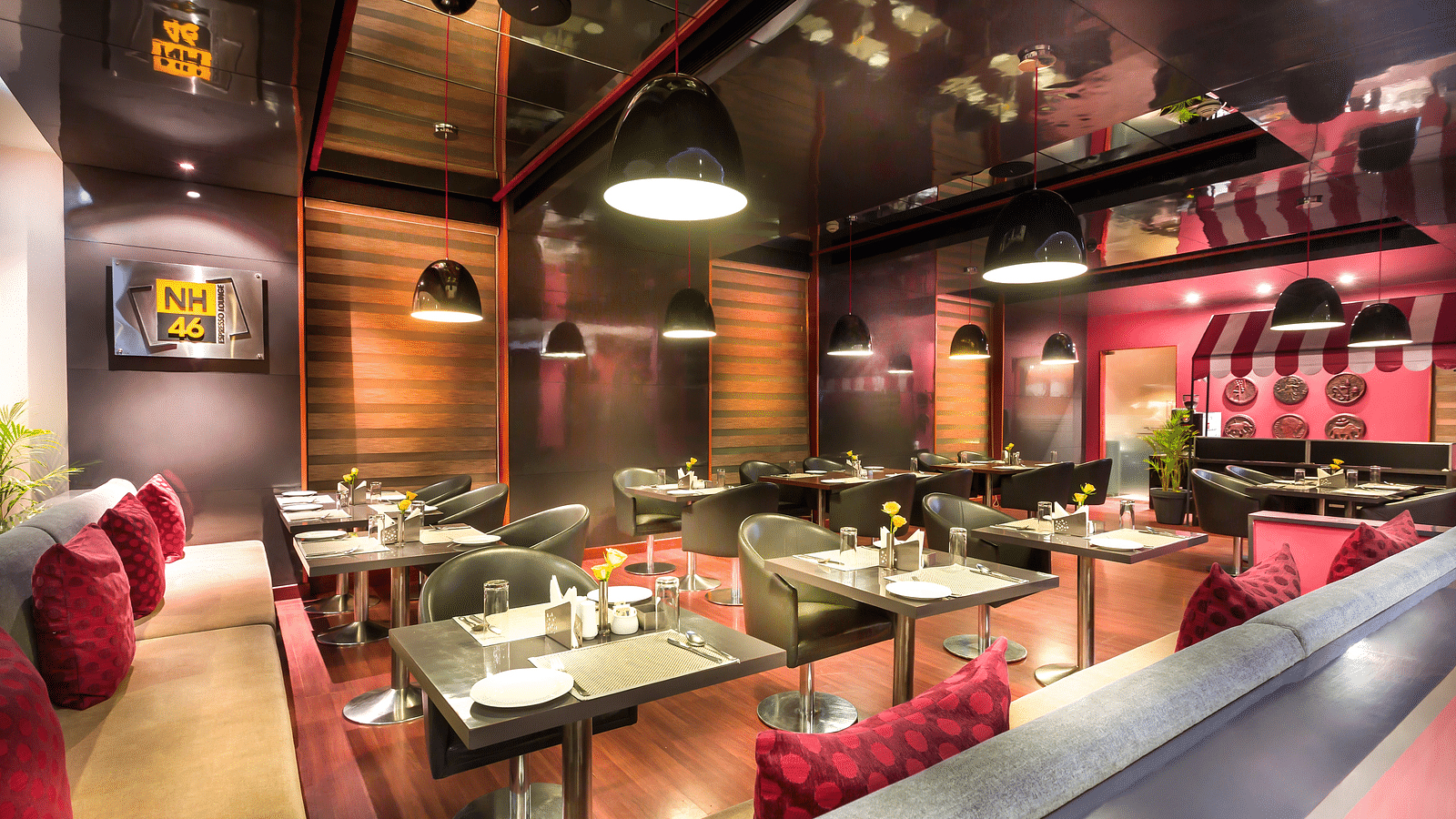 Modern restaurant interior with red accents, plush seating, and a reflective ceiling.