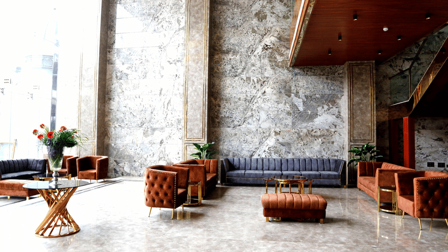 A brightly lit waiting area in the lobby of Leroy Grand, Yeshwanthpur, featuring tufted couch sets with a coffee table in the middle.