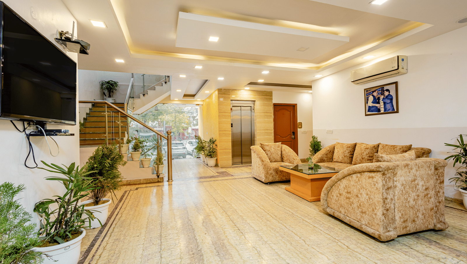 A wide view of the sofas and TV screen in the lobby of Lime Tree Hotels and Banquet Hall Near Huda Metro, Gurgaon