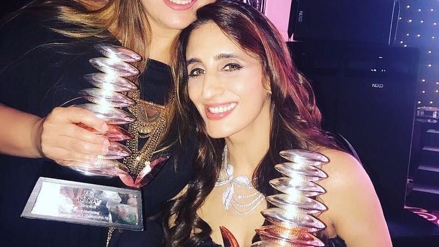 Kiran Bawa receiving an award with a celebrity - IOSIS Spa & Wellness