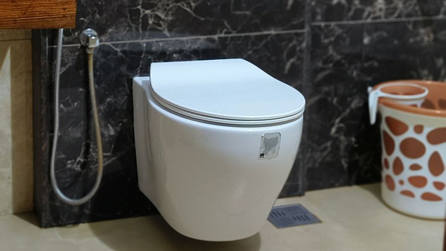 Front view of a W/C with a bucket on side in the washroom at 102 room at Ananda Holiday Home, Wayanad 3