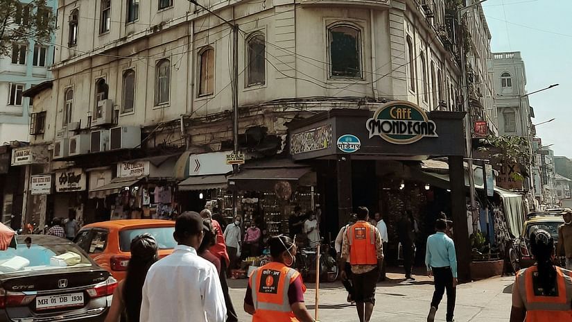 image of the colaba causeway in mumbai featuring a tall building with cafe mondegars in the ground floor