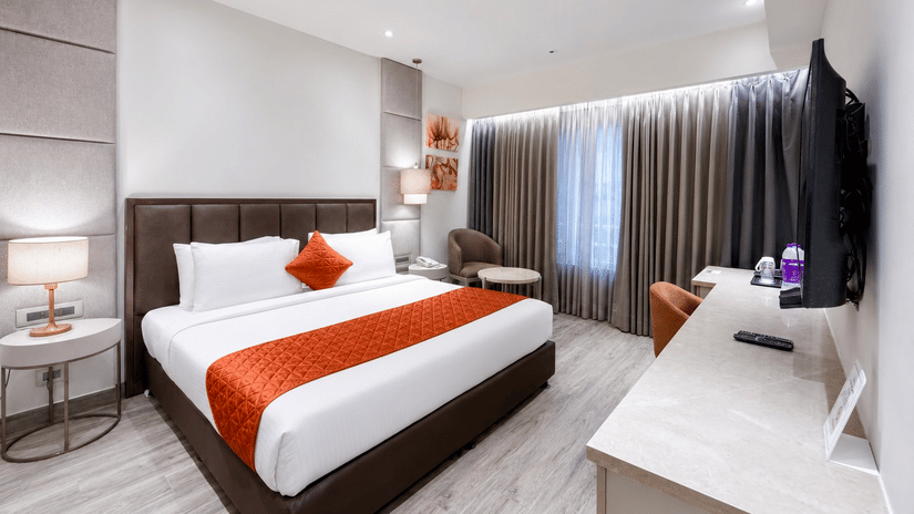 Premium Room with a king bed, wall-mounted TV, and a functional work desk at Hotel Saket 27, offering a modern and comfortable stay.