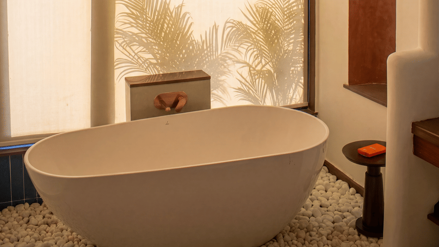A luxurious bathroom featuring a standalone oval bathtub, large window, and wooden stool at The Sierra - By The Lake.