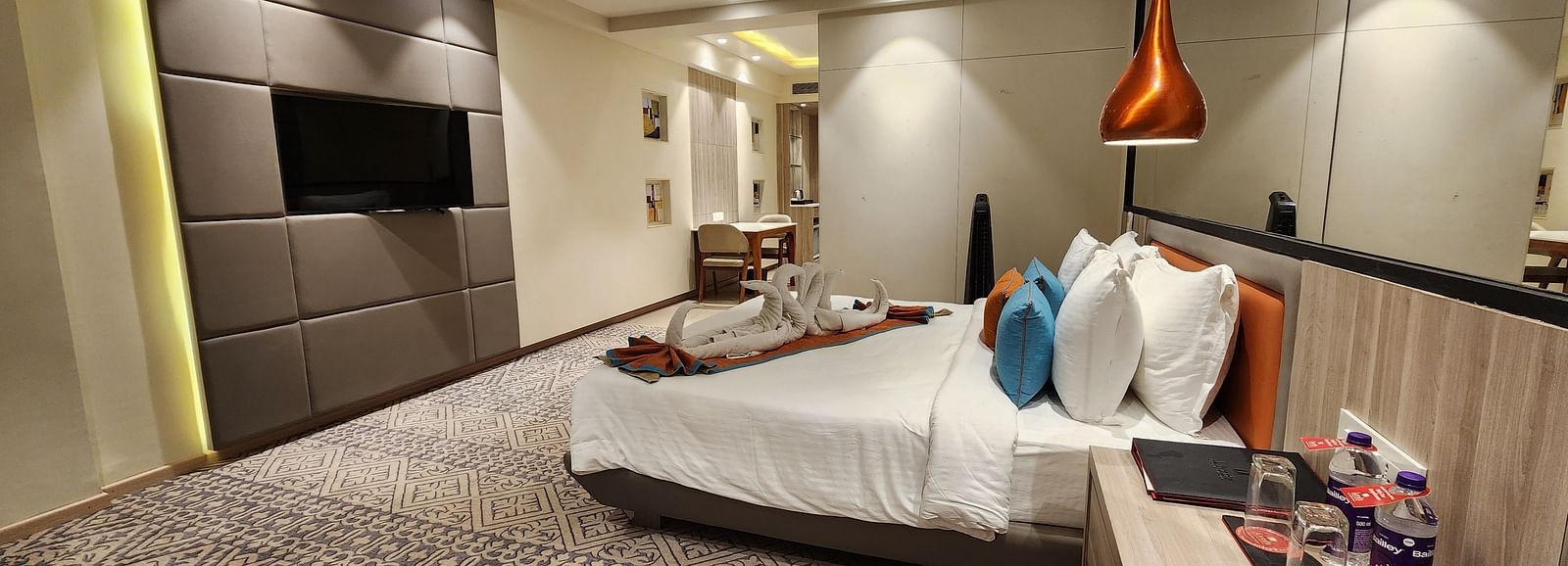Elegant hotel room with a king-sized bed, bedside tables, modern wall art, and a mounted flat-screen TV.