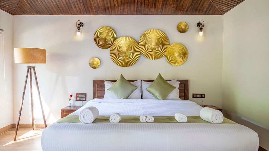 A view of a large bed in our suite with a night lamp by the side - Stone Wood Nature Resort, Gokarna