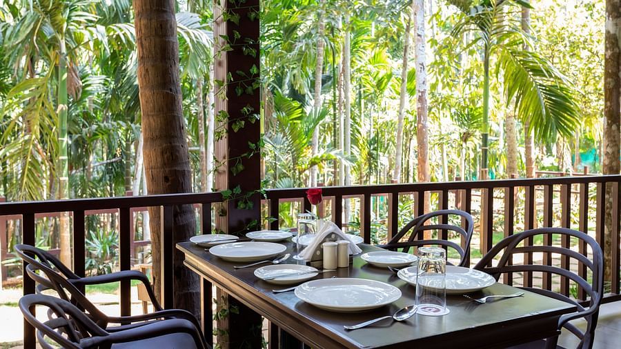 A dining table with plates and cutlery placed on it in an open air restaurant - Stone Wood Nature Resort, Gokarna