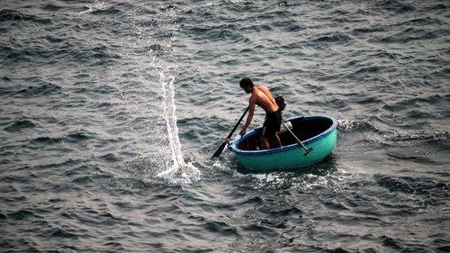person in a coracle boat paddling