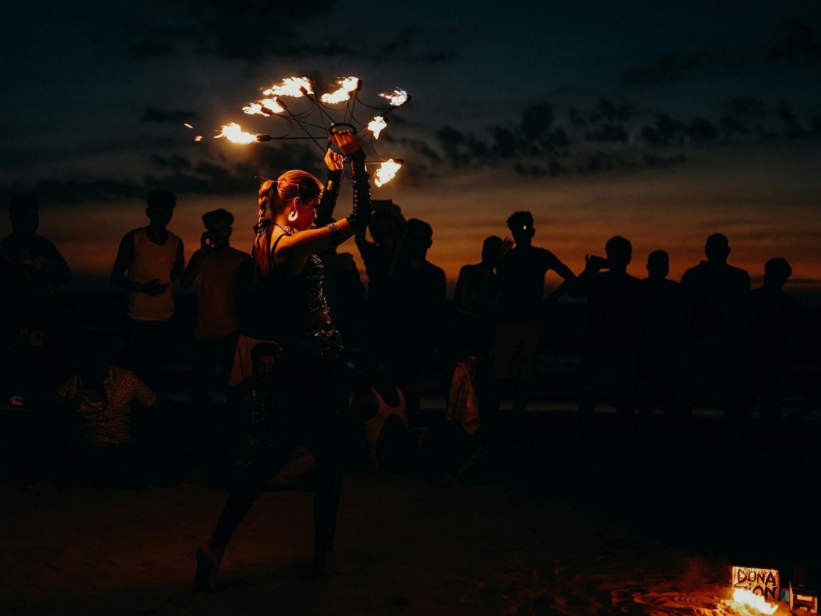 A person performing an act with fire at a beach at dusk