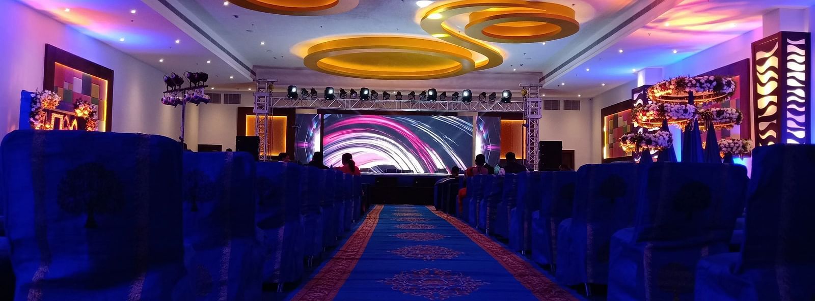 Long hallway with carpet, stage, and ceiling decor.