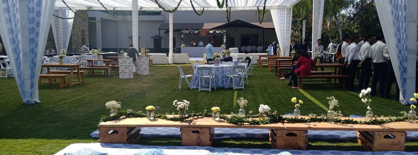 Outdoor event setup with a tent, tables, chairs, and decorations on a lawn. - Bamboo Saa, Udaipur