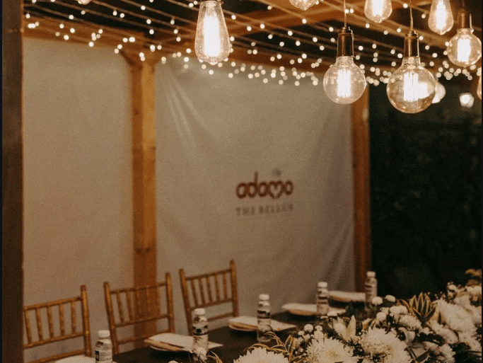 A flower decorated seating for a night event with hanging lights .
