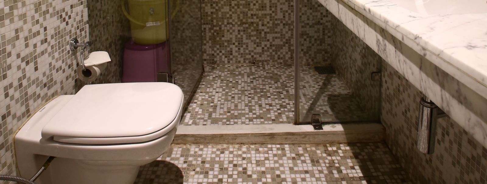 bathroom with a wide mirror, sink, commode and a shower with glass door