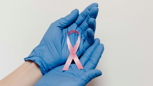 Two gloved hands gently hold a ribbon, folded to symbolise cancer.