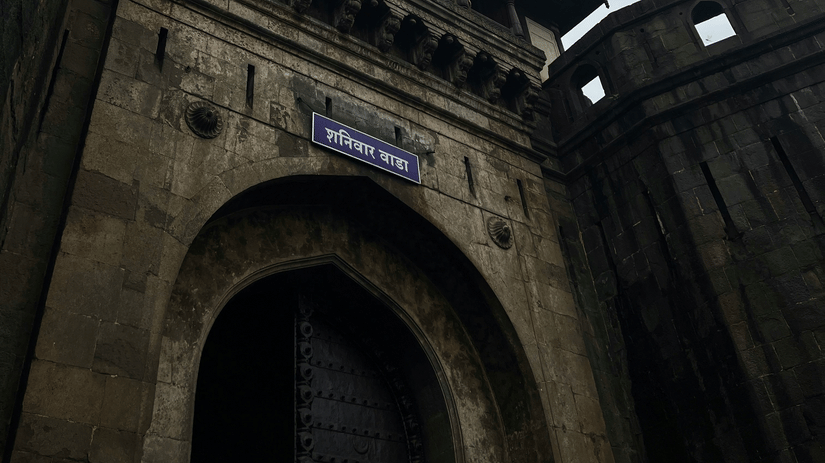 Upward view of the historic entrance and stone walls of Shaniwar Wada in Pune.