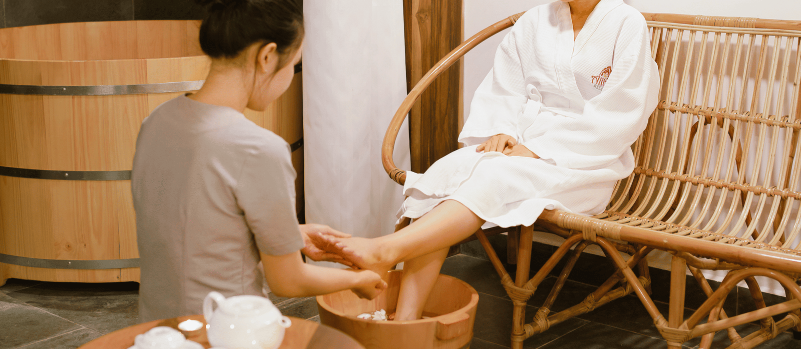 A woman receiving pedicure by another woman in a wooden furnished room in at Alibu Resort - Vietnam seaside resorts