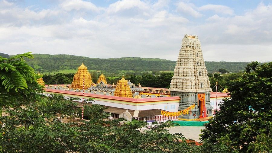 South Indian temples surrounded by trees and hills. Above them is an open sky.