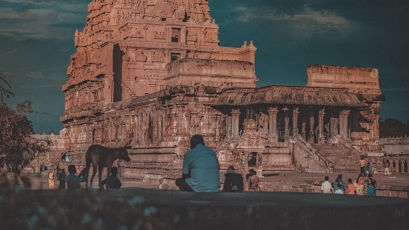 A hindu temple with intricate architecture outside on the roof as seen from a distance.
