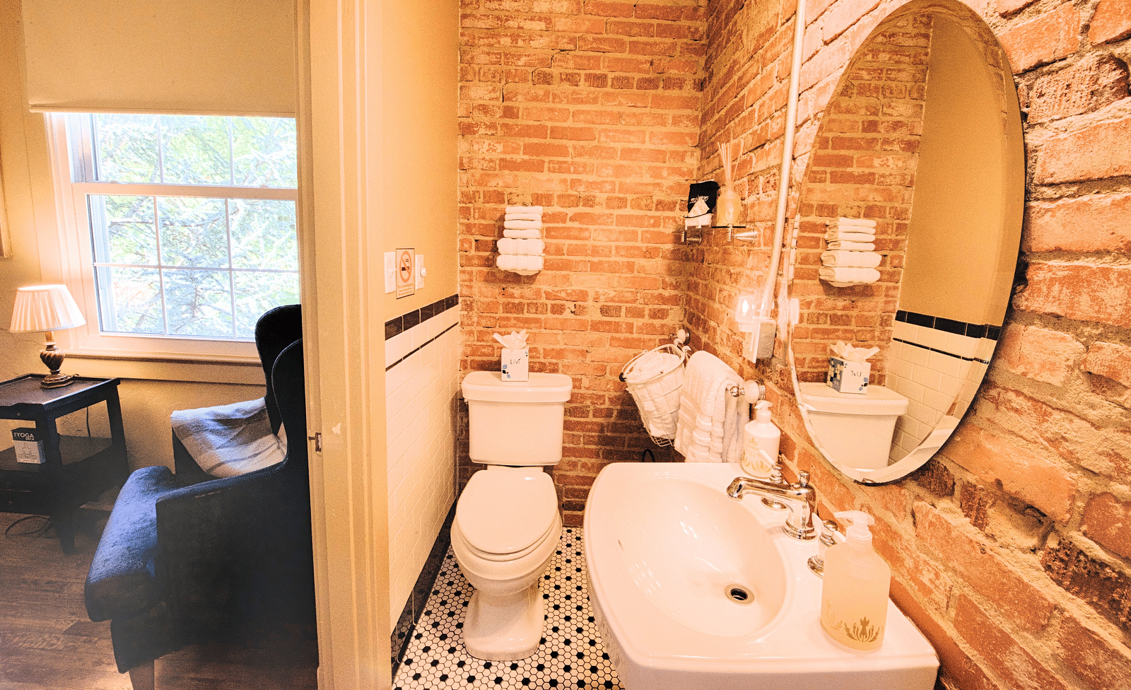 a cozy bathroom with huge curcular mirror above the wash basin and a commode in the corner - Historic Tapoco Lodge