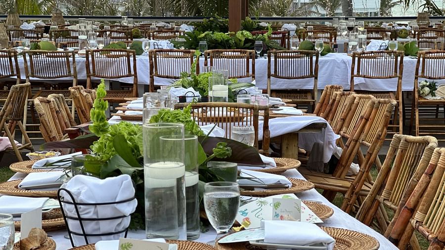An open dining area featuring dining tables paired with chairs. The area is organized for big events like weddings as the tables have bouquets and other decorative elements along with plates and cutlery.