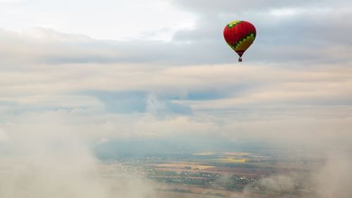 A hot air balloon amidst clouds shot from an aerial view