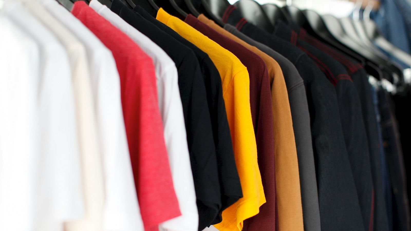 a close up image of various coloured t-shirts hanging at a store