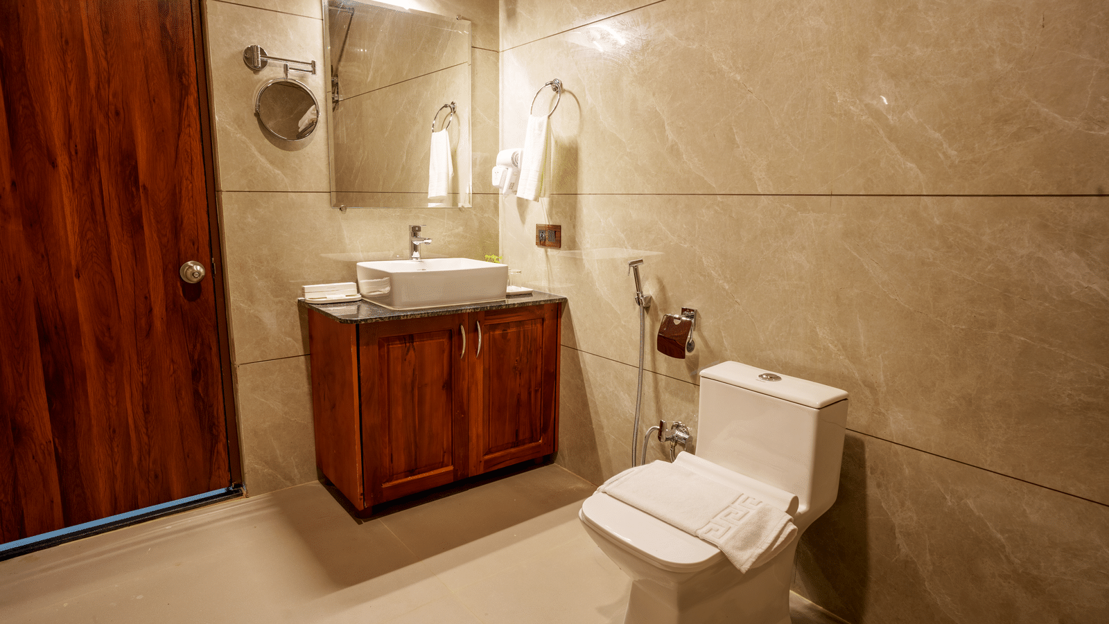 Modern bathroom with a white toilet, sink, mirror, and wooden cabinet.