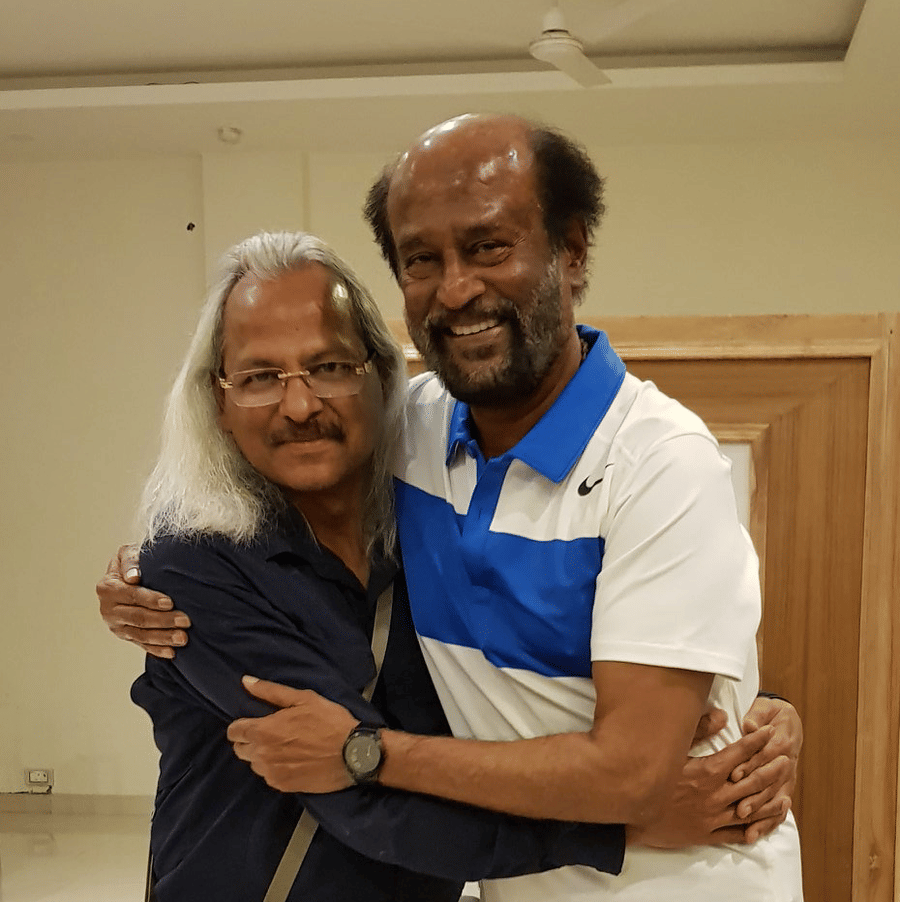 Rajnikanth, a tamil movie superstar, hugging the owner of Shaheen Bagh and posing for a picture inside a room.