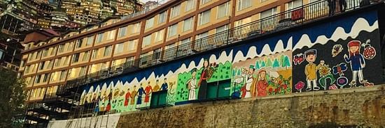 Several mountain-life-related artworks placed next to a wide building - The Orchid Hotel Shimla
