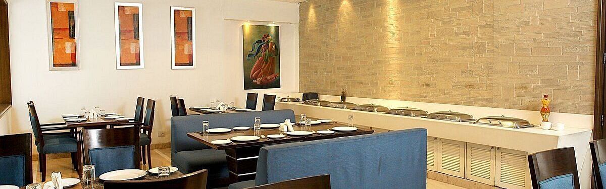 Tables and chairs neatly arranged with cutlery set on the table at Café Inde, Inde Signature Tower, Gurgaon