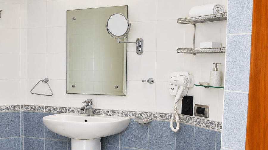 Bathroom with a vanity sink, wall mirror, and blue tiled accents at Chariot Beach Resorts, offering a clean and functional guest space.