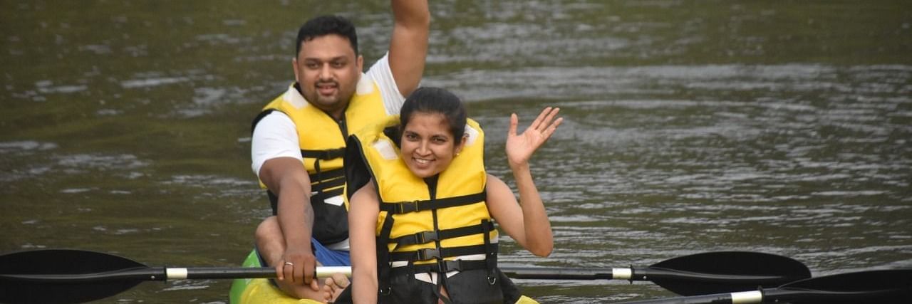 Couple kayaking on a river, joyfully waving at the camera - Evergreen County