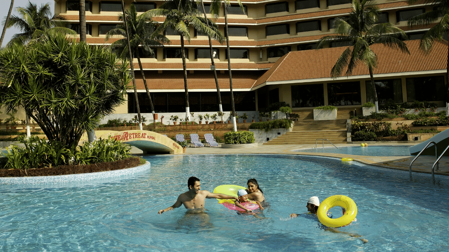 The Retreat Hotel and Convention Centre exterior view showing the large swimming pool with guests relaxing, surrounded by landscaped greenery and the hotel building in the background.